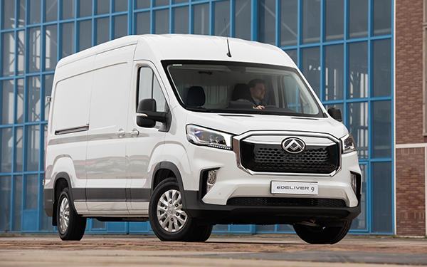 Ein weißer Lieferwagen von eDeliver 9 vor einem modernen Gebäude mit großen Fenstern.