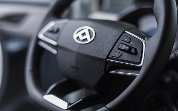 Nahaufnahme eines modernen Lenkrads mit einem Markenemblem und Bedientasten.