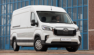 Weißer Lieferwagen mit Fahrer, steht vor großen Fenstern in einem modernen Gebäude.